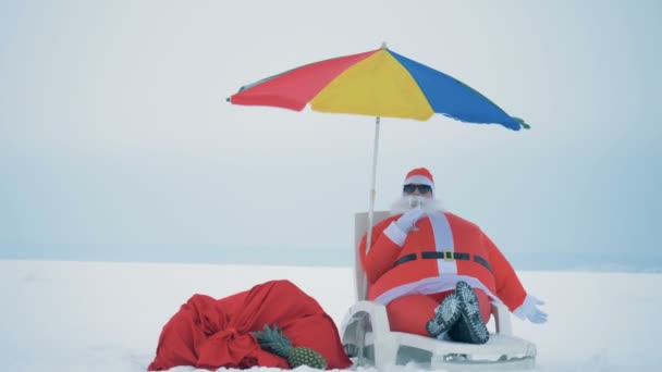 Avkoppling av jultomten sitter i en solstol och dricker champagne — Stockvideo