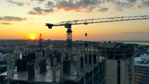 Een kraan werkt op bouwplaats op zonsondergang achtergrond. — Stockvideo