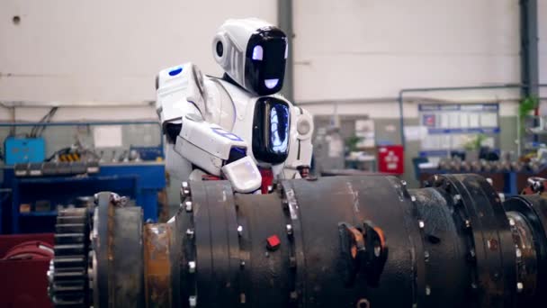 Een cyborg gebruikt schroefpistool om met metalen details te werken in een fabriek. — Stockvideo