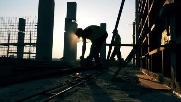 Planta de construcción con un ingeniero soldando tallos metálicos — Vídeos de Stock