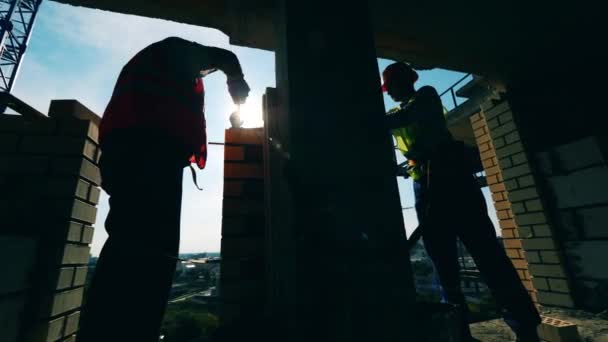 Масонские работы, проводимые двумя инженерами в высотном здании — стоковое видео