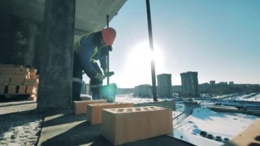 İnşaat alanında çalışırken bir adam tuğla örüyor. İnşaat alanı, inşaat endüstrisi, inşaat işçisi konsepti.