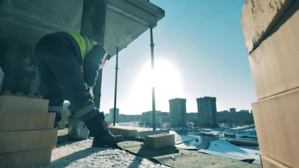 L'homme pose des briques tout en travaillant dans un bâtiment inachevé . — Video