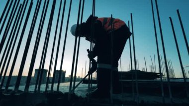 Üniformalı bir adam bitmemiş binada zemini deliyor. İnşaat alanı, inşaat endüstrisi, inşaat işçisi konsepti.