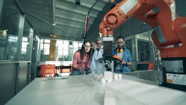 Des analystes scientifiques observent une expérience avec un robot — Video