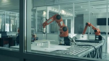 Mekanik kollar bir robot laboratuvarında görevler yapıyor.