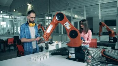 Bilim analistleri hareket halindeki bir robot pençeyi inceliyor. Modern eğitim, yenilikçi eğitim, mühendislik eğitimi, bilim eğitimi kavramı.