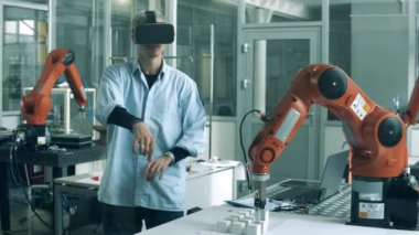 VR gözlüklü erkek analist bir robot mekanizmasını yönetiyor