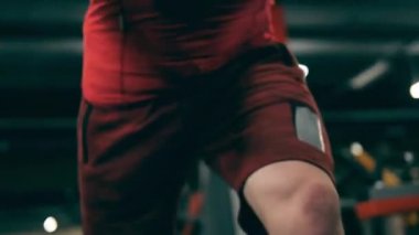 Erkek sporcu spor makinesiyle kollarını esnetiyor.