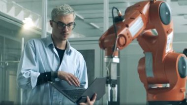 Genç bilim adamı hareket halindeki bir robot pençesini gözlemliyor.