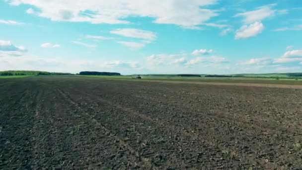 Червоний трактор їде на сільськогосподарському полі, оранка землі . — стокове відео