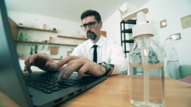 Man maakt gebruik van gel sanitizer tijdens het werken op laptop. — Stockvideo