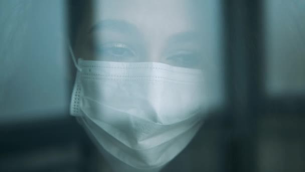 Vrouw kijkt door het raam binnen terwijl ze een masker draagt. — Stockvideo