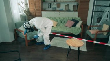 İşçi salgın sırasında bir odada mobilya siliyor.