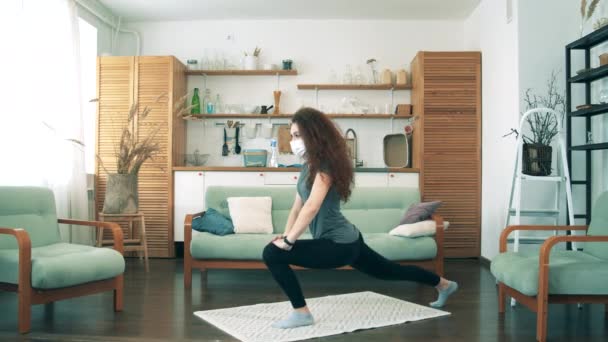 A girl in medical mask stretches at home. — Stock Video