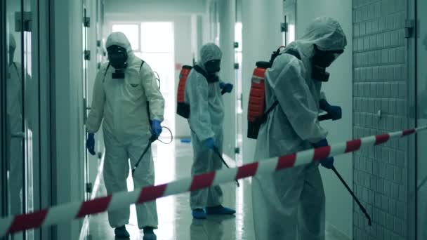 Drie arbeiders desinfecteren gang om zich te ontdoen van virussen. — Stockvideo