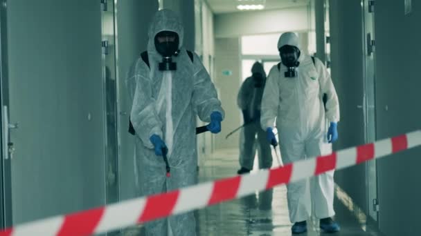 Tre operai spruzzano il corridoio per disinfettarlo. — Video Stock