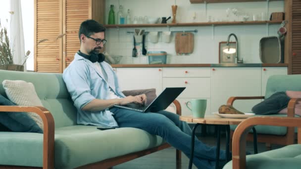 한 남자는 노트북 과 전화를 사용하여 집에서 일한다. — 비디오