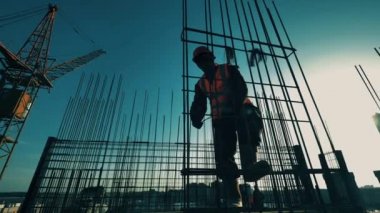İnşaat işçisi çatıda bir metal iskelet yapıyor.