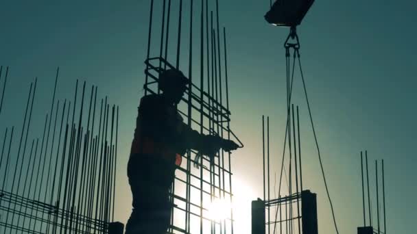 Builder werkt met een metalen raamwerk bovenop een gebouw — Stockvideo
