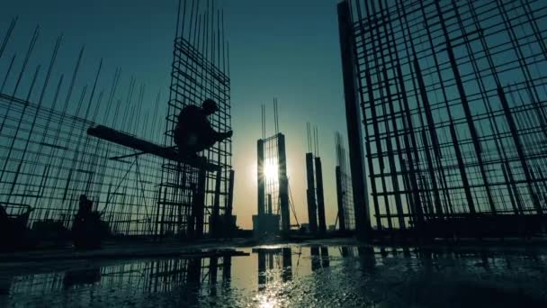 Telhados ao pôr do sol com um trabalhador construindo uma estrutura — Vídeo de Stock