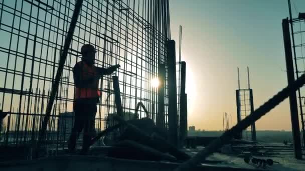 El experto en construcción está ajustando la carcasa metálica de un edificio. Industria de la construcción, proyecto de construcción, proceso de construcción durante la puesta del sol . — Vídeos de Stock