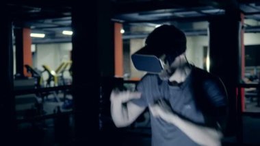 Spor salonunda VR gözlüklü sporcu boks yapıyor.