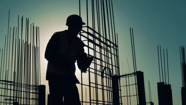 Byggaren arbetar med en metallstomme vid solnedgången — Stockvideo
