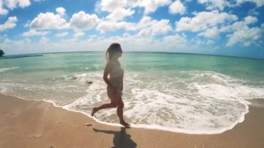 Kız sahilde koşuyor, tatilin tadını çıkarıyor..