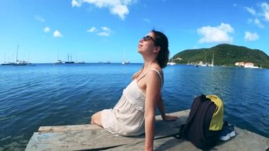 Gülümseyen kadın tatilin tadını çıkarıyor, okyanusun kenarında oturuyor..