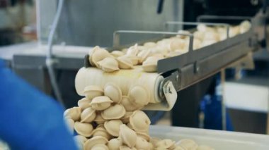 Çiğ hamur köfteleri taşıyıcıdan tepsiye düşüyor.