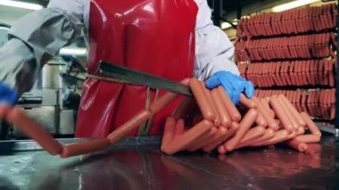 Fabrika çalışanı metal bir çubuğa sosis döküyor.