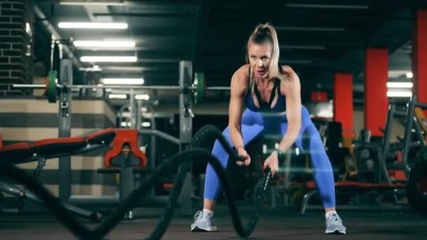Female athlete workouts with battle ropes. — Stock Video