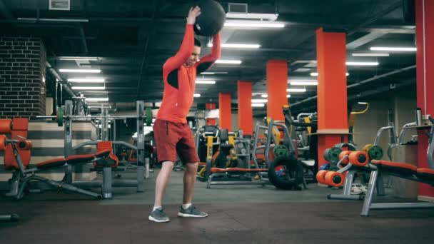 Entrenamientos de hombre con una pelota en el gimnasio crossfit . — Vídeos de Stock