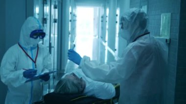 Tehlikeli madde uzmanları hastanede bir adamı sedyeyle muayene ediyorlar. Coronavirüs salgını konsepti.