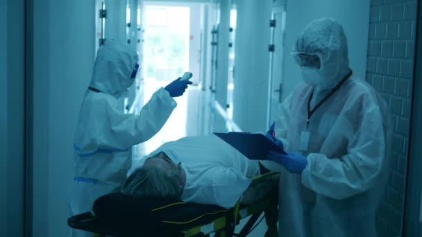Dois médicos tratam um paciente em maca durante a pandemia de coornavirus . — Vídeo de Stock