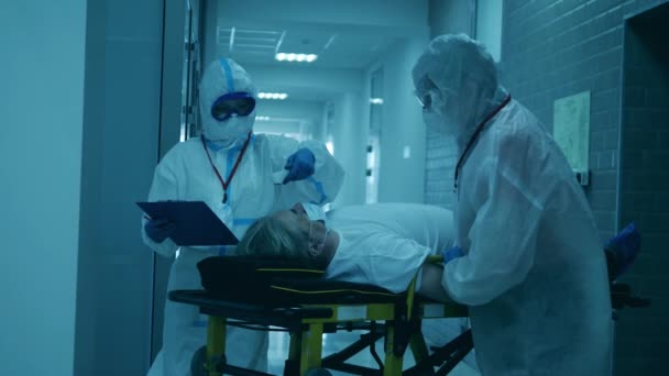 Работники больницы проверяют температуру человека в условиях пандемии. — стоковое видео