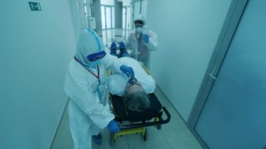 Sağlık görevlileri, koronavirüs salgını sırasında hastanede sedye taşıyan bir adamı taşıyorlar..