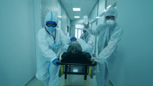 Dokters helpen een man met het coronavirus door hem over te brengen op een brancard. Coronavirus covid-19 geïnfecteerde patiënt in een kliniek. — Stockvideo