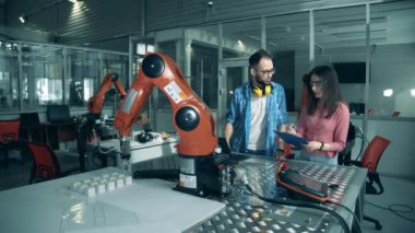 Yazılım uzmanları çalışan bir robotik kolu gözlemliyorlar