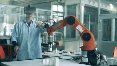 VR gözlüklü erkek geliştirici yüksek teknolojili robotla çalışıyor.