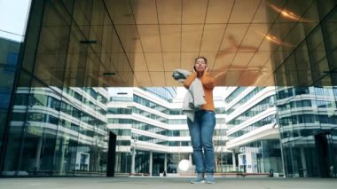 Bir kadın müzik dinlerken modern bir şehir bölgesinden ayrılıyor.