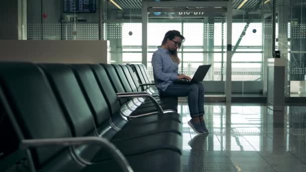 Una señora está usando su portátil mientras espera su vuelo — Vídeo de stock