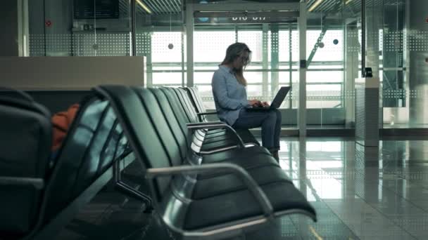 Красуня чекає на політ і використовує свій ноутбук — стокове відео