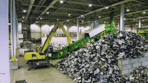 Prullenbak, e-waste, elektronische afval recyclingfabriek. Een graafmachine en stapels afval in een recyclinginstallatie. — Stockvideo