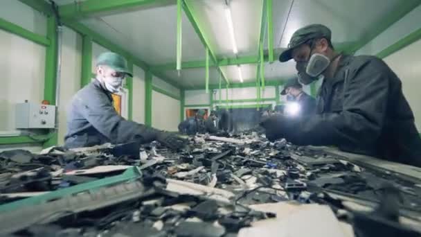 Mannen sorteren metalen afval op een transportband. Recyclusproces, secundair gebruik van kunststof. Prullenbak, e-afval, fabriek voor elektronische recycling van afval. — Stockvideo