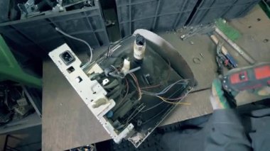 Erkek işçi fabrikadaki geri dönüşüm monitörünü yok ediyor. Çöp, e-atık, elektronik çöp geri dönüşüm fabrikası..