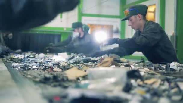 Recycling center arbeiders sorteren afval op een transportband. — Stockvideo