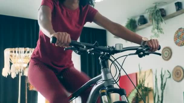 Afrykanka ćwiczy na rowerze treningowym w domu — Wideo stockowe