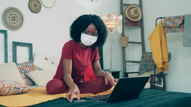 Femme africaine dans un masque facial fait du shopping sur Internet — Video